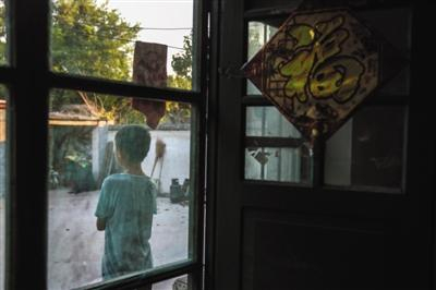 　　8月8日，山东郓城县西张楼村，张超12岁的弟弟独自一人站在屋外望着大门口。他的父亲前往天津询问案情进展未回，母亲因极度悲伤卧床不起，屋里屋外全靠弟弟张罗。新京报记者 彭子洋 摄