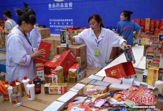 资料图：工作人员正在将假冒伪劣的茅台、五粮液等酒包装拆开。 中新社记者 刘忠俊 摄