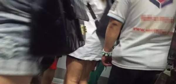 图为一名戴着黄色手链的中年男子不时碰触前面女士的臀部。