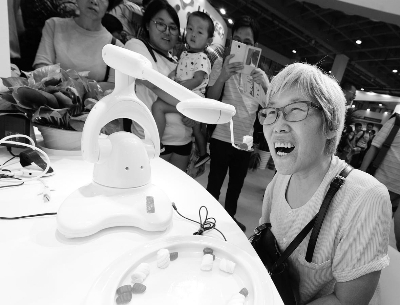 一位老人正在体验养老机器人的喂饭功能。法制晚报 林晖 摄