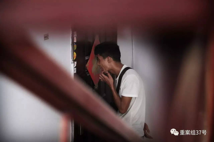 ▲8月19日，江苏省丹阳市商业街23号楼某单元401，薛涛（化名）正趴在猫眼儿上试图了解屋内是否有人。