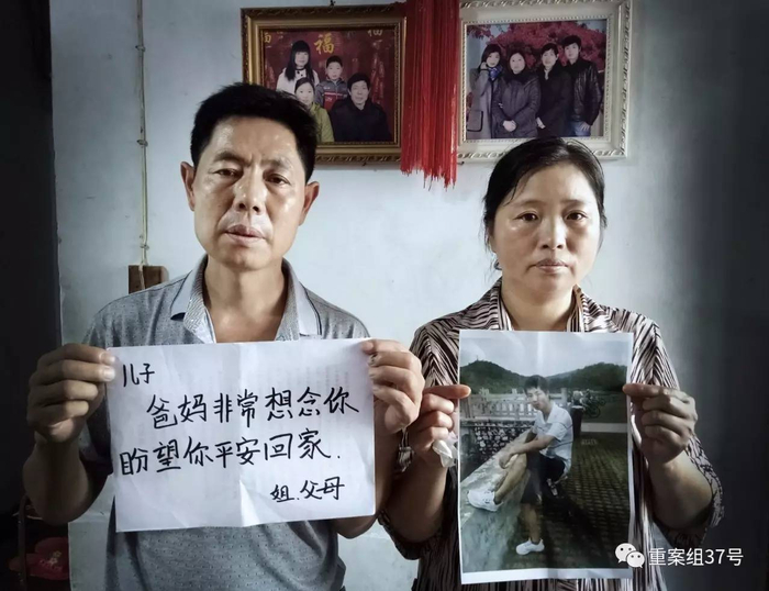 ▲8月20日，河南信阳，邓杰的家中。邓杰的父母拿着儿子的照片以及盼望儿子平安回家的话。背后墙上是其全家福。&nbsp;
