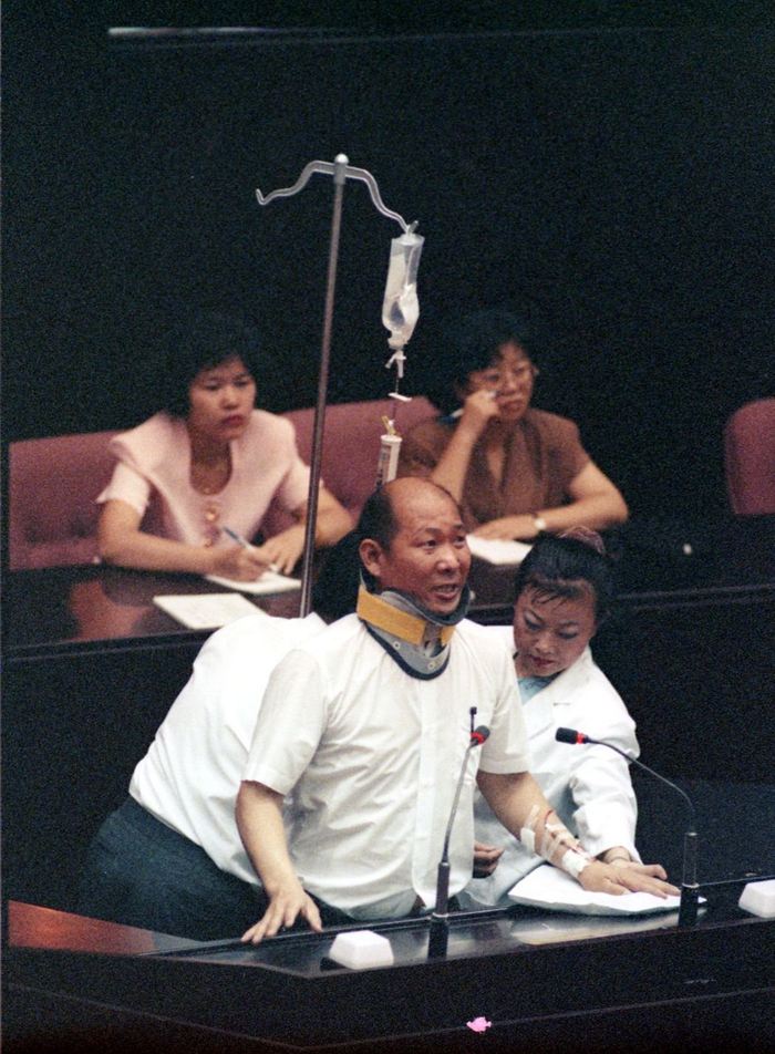 核四预算案引发的朝野流血冲突，“立委”施台生吊着点滴由护士陪同上发言台。（图片来源：台湾《联合报》）