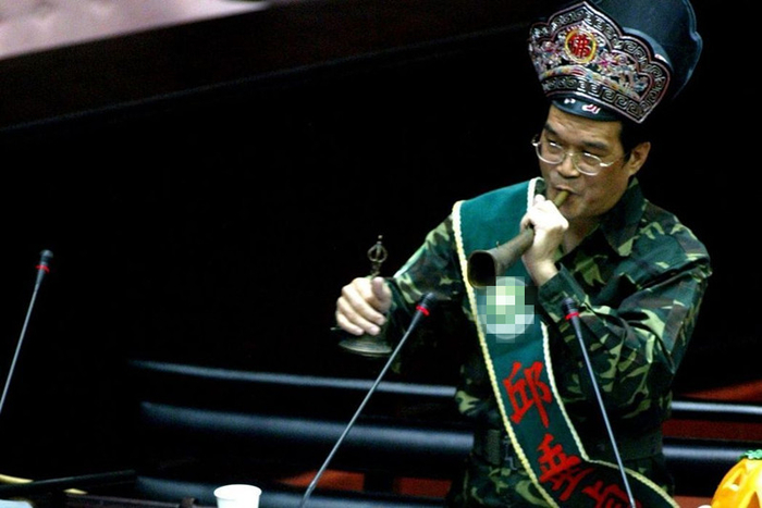 民进党“立委”邱垂贞当年质询时身穿迷彩服，头戴道士帽，拿起法器表演抓鬼秀。（图片来源：台湾《联合报》）