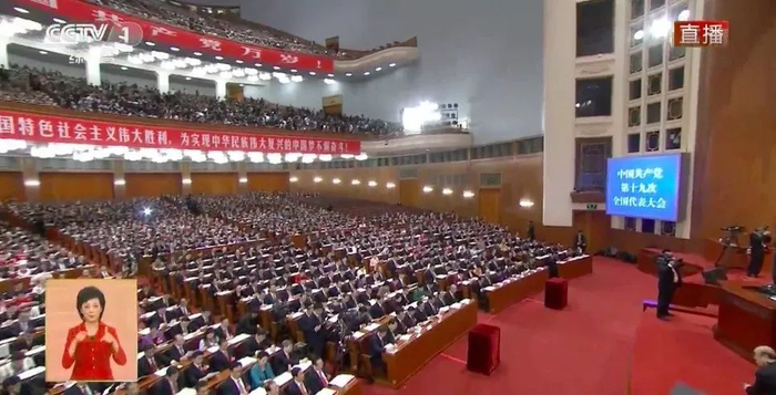 作为十九大开幕式上的直播手语翻译，周晔出现在屏幕左下角。图片来自央视视频截图。