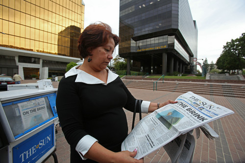 资料图片：2012年7月12日，在美国加利福尼亚州圣贝纳迪诺市市政厅门前，一名妇女在看报。新华社发
