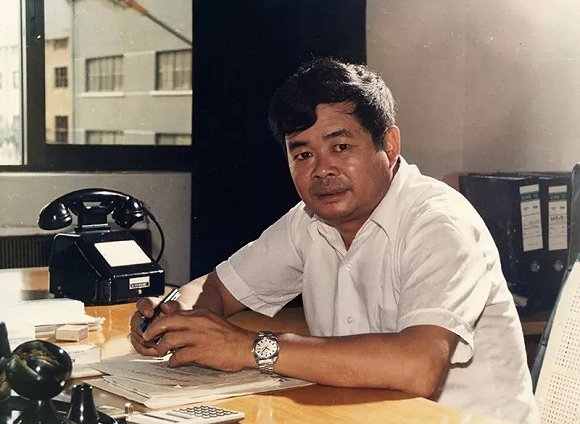 ▲&nbsp;1988 年夏天，曹德旺在办公室留影，桌上的摇号电话记录着时代的变迁