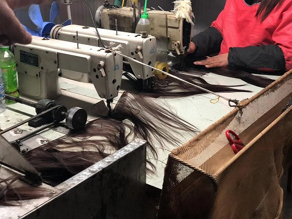 工人们正在把处理好的头发打成发片，方便下一步织到发网上。图片拍摄：刘雨静