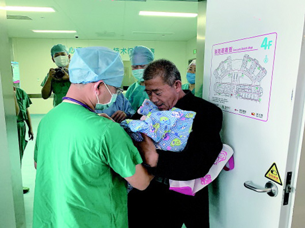 　25日，黄先生从医生手中接过女婴。 齐鲁晚报 图