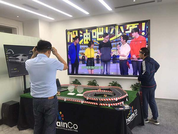  有员工正在用智能头环测试专注力集中下的小车奔跑速度。