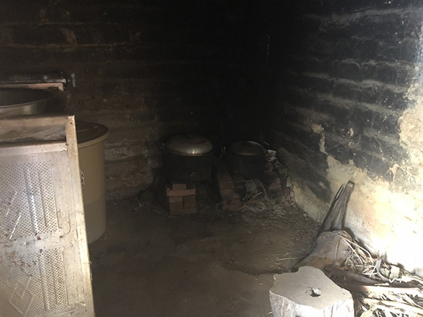 小文一家用柴火做饭，厨房一角已被熏黑。