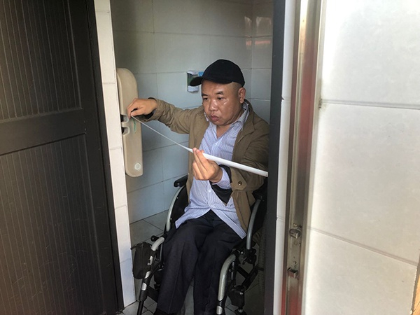 郭兵对无障碍厕所门进行测量。