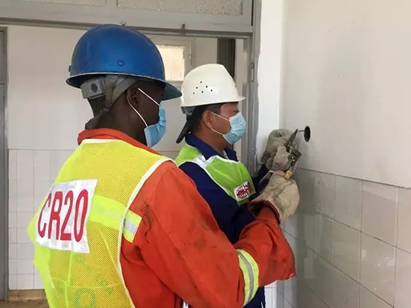 中外施工人员正在重新布设电线。