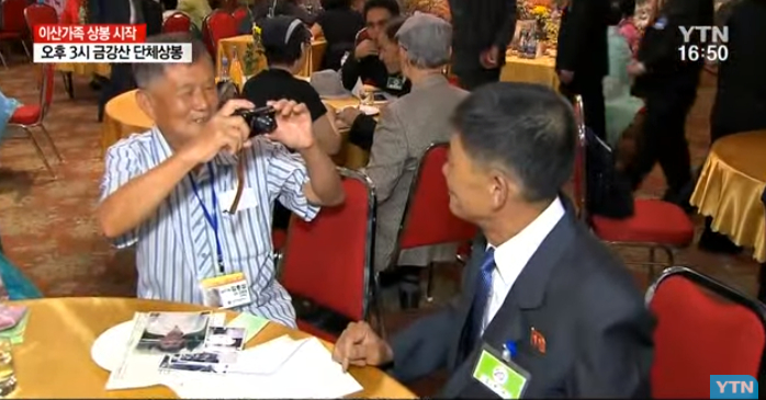 老人掏出相机，给异国亲人拍照。（韩国YTN电视台）