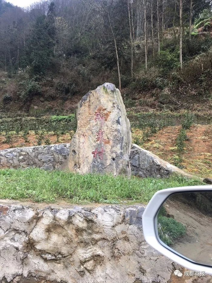  △张晓清立于斯栗村口的“村碑”。罗敏摄