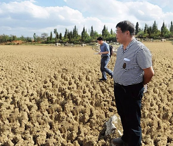 ▲&nbsp;2010 年 5 月，曹德旺在云南省陆良县天生坝水库考察旱情，干涸的土地已经完全龟裂。这一年，他为旱情严重的西南五省市捐款 2 亿元，该项捐款惠及 10 万户受灾家庭