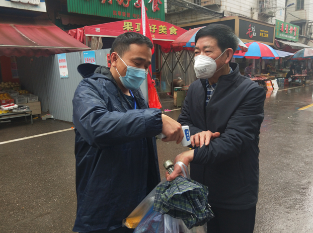 　　彭卫华(左)在测量进出居民的体温