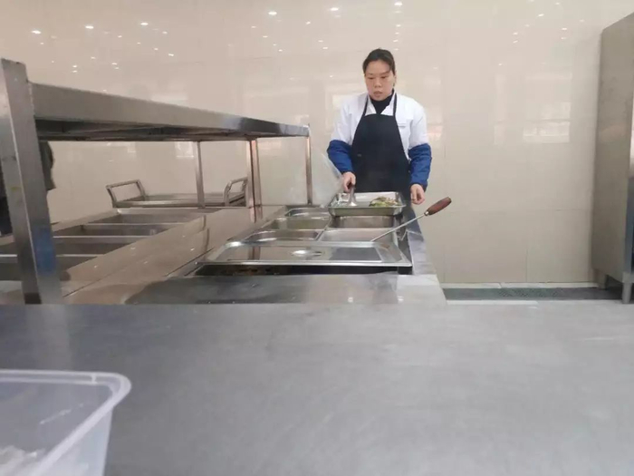  食堂内的工作人员在准备菜品。 陈抒怡 摄