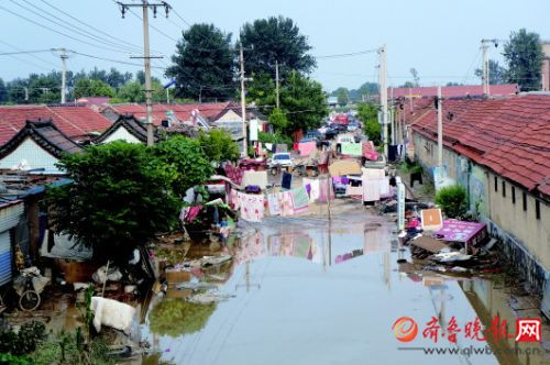 21日，寿光上口镇口子新村受灾严重，村中积水逐渐退去，村民们趁天好抓紧晾晒衣物。 本报记者 陈文进 摄