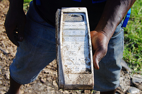 在加纳首都阿克拉的阿格博罗什地区，一名拾荒者展示一台废旧微波炉的控制面板。（新华社）