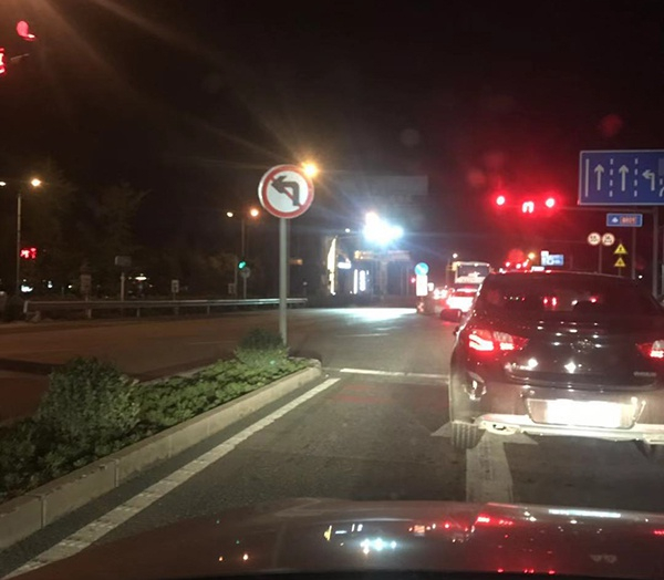 图中的射灯设置在马路对面的路口，用于照射车辆尾部，对观察路口状况造成了一定影响。