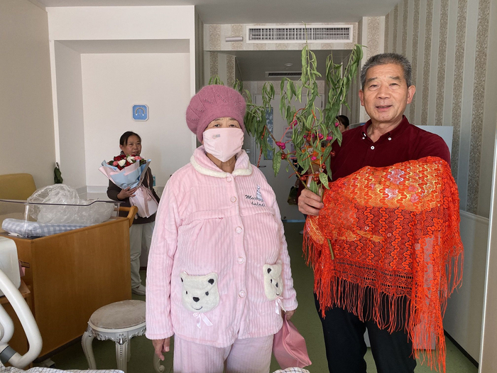 出院前，黄维平手拿桃树枝，与妻子和女儿一起拍照留念。新京报记者&nbsp;祖一飞 摄