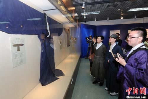 　　资料图：图为来自台湾鹿山文社的汉服爱好者认真观看展出的一件按文物还原的袖展345厘米、衣长200厘米的绀青色绢复袍。中新社发 刘可耕 摄