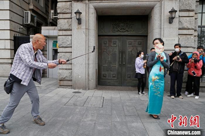 摄影爱好者在上海外滩街头，拍摄春秋航空“春之翼”旗袍队乘务员。　殷立勤 摄