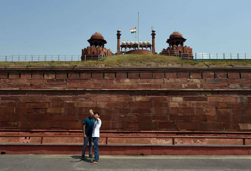 资料图：在印度首都新德里，两名游客在红堡外墙合影。（新华社）