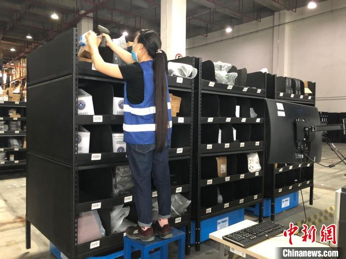 英迈供应链工作人员从机器人货物柜上取物。　朱族英 摄