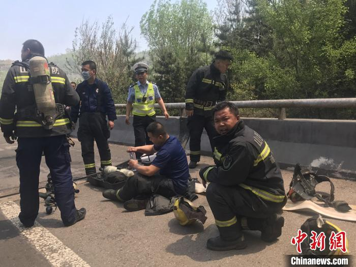 大火被扑灭后，一名消防员累得坐在发烫的路面上补充水分。　周洋 摄