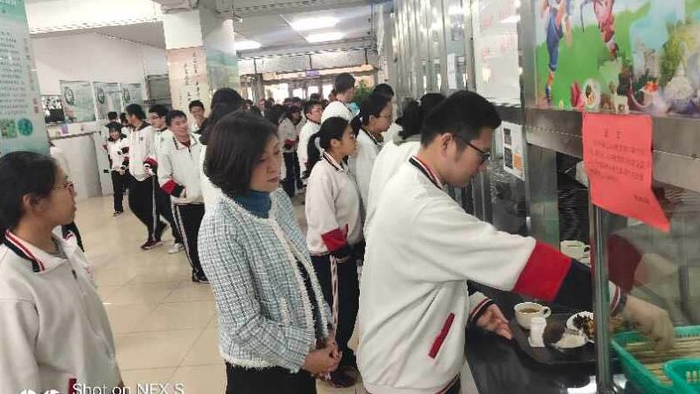 陈经纶中学高中校区校长牟成梅在食堂与学生一同排队取餐。 校方供图