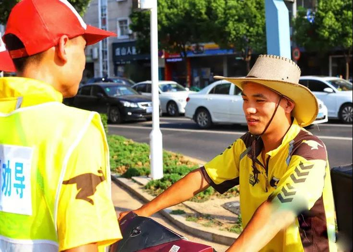 （外卖小哥当交通协管员，提醒路过同行遵守交规）