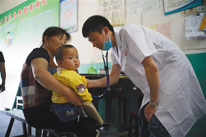 ▲6月7日，余水在金寨县南溪镇的卫生所里为孩子检查身体。