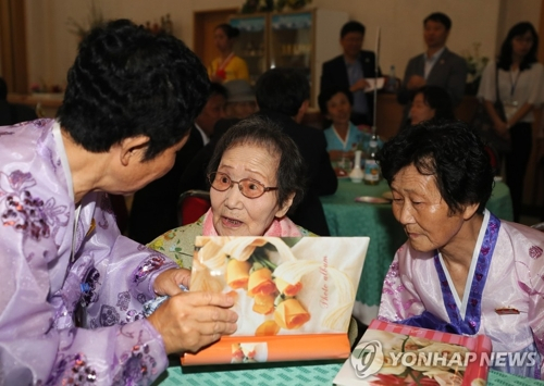 韩方99岁高龄的韩信子与两个在朝女儿翻看相册（图片来源：韩联社）