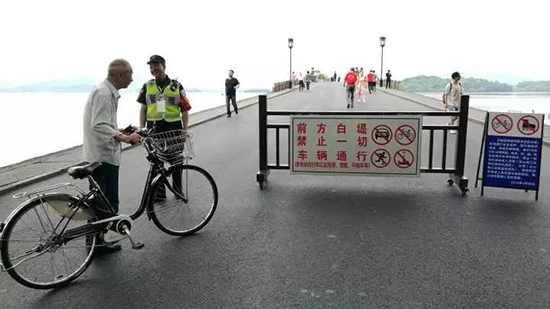 白堤出口，断桥。今晨，岳庙管理处的保安正在劝阻非机动车进入白堤。