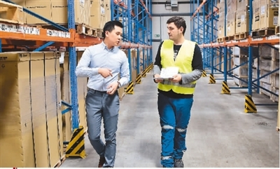 在德国杜伊斯堡渝新欧（重庆）物流有限公司的物流仓库，公司商务主管甘宇辰（左）同一名外籍雇员进行业务沟通。　新华社记者 逯 阳摄