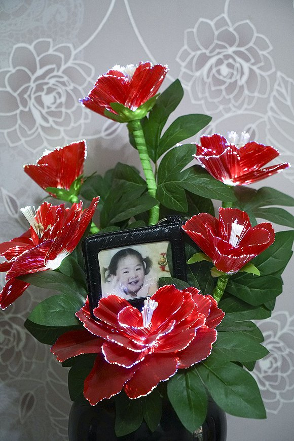 会发光的电子花瓣内是李桂花遇难的外孙女三岁半时的一张照片。摄影：吕萌