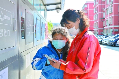 分拣员指导居民扫码操作投放机。