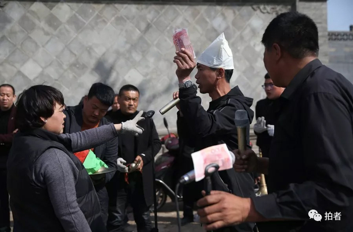  △&nbsp;一场葬礼上，主家正在给表演者打赏。