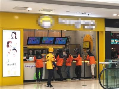 4月12日，一家饮品店门前等待取外卖的滴滴外卖骑手与路过的美团外卖骑手。B04-B05版摄影/新京报记者 陈维城