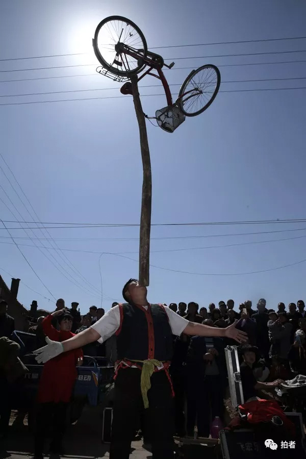 △&nbsp;三平用下巴将一根大木棍顶在空中，木棍的顶端还顶着一辆自行车。