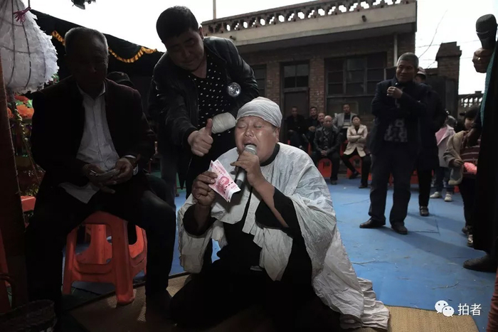 △&nbsp;三平跪在灵前哭唱，主家送上赏钱后对其伸出大拇指表示称赞。