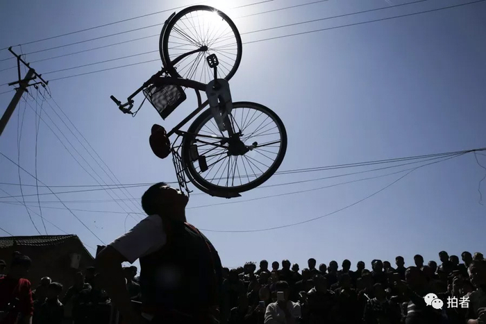 △&nbsp;三平用下巴将一辆自行车顶在空中。