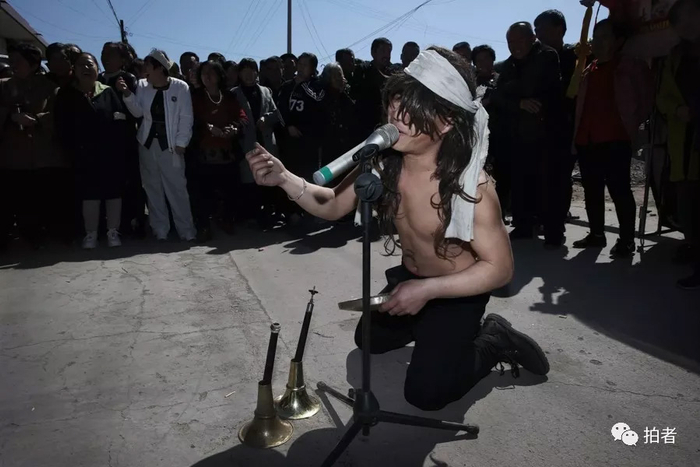  △&nbsp;董鹏一边通过麦克风“嚎啕大哭”，一边伸出右手做数钱的动作，引得围观的人们哈哈大笑。他这是为了向主家要赏钱。