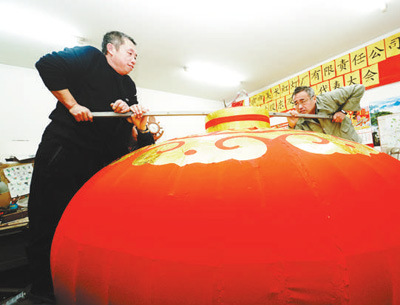 　准备使用前，两名工人压开灯笼。本报记者贺勇摄。