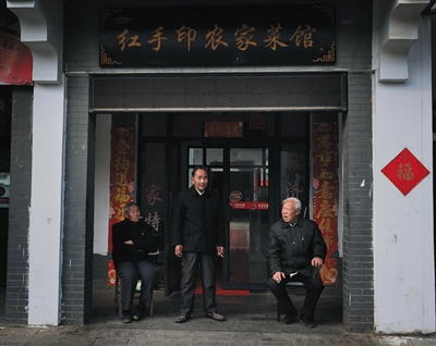 严国品、严立华和严俊昌（从左往右）在严立华家开的餐馆门口聊天。