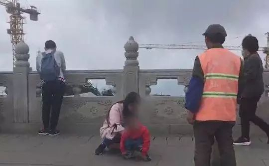 　男童在峨眉山景区金顶平台的地上大便。