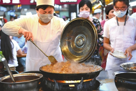 6月2日，在河南省开封市鼓楼夜市，一名小吃摊主在制作传统小吃炒凉粉。新华社发