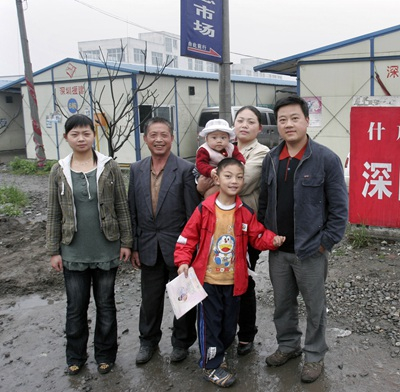 2009年5月8日，四川省什邡市，在地震中受灾的徐兴蓉全家在自家板房小区门口。2008年8月8日，徐兴蓉在什邡产下“奥运宝宝”。张晓理/摄